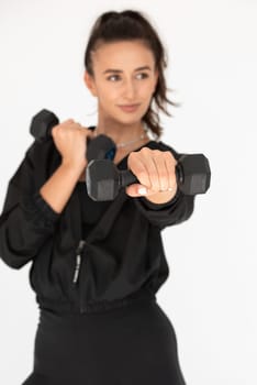 Young girl posing with dumbbells for power training, indoors. athlete wearing black leggings and shirt.