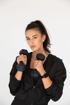 Young girl posing with dumbbells for power training, indoors. athlete wearing black leggings and shirt.