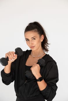 Young girl posing with dumbbells for power training, indoors. athlete wearing black leggings and shirt.