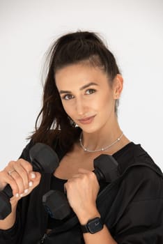 Young girl posing with dumbbells for power training, indoors. athlete wearing black leggings and shirt.