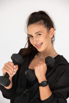 Young girl posing with dumbbells for power training, indoors. athlete wearing black leggings and shirt.