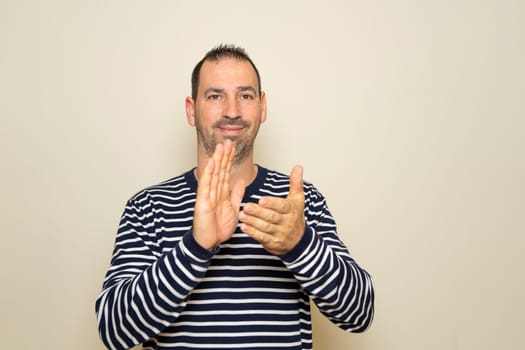 Bearded hispanic man about 40 years old isolated over beige background applauding after his presentation at a conference.