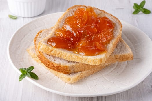 Apricot jam on bread in a white plate.