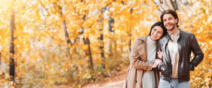 Peaceful smiling couple enjoying beauty of autumn forest together, looking at copy space