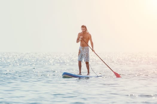 Man Sea Sup. Strong athletic man learns to paddle sup standing on board in open sea ocean on sunny day. Summer holiday vacation and travel concept. Aerial view. Slow motion.