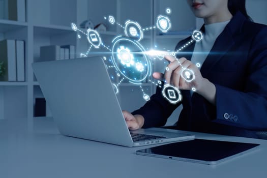 Businesswoman using a laptop with a futuristic digital interface, showcasing technology and innovation in a modern office environment.