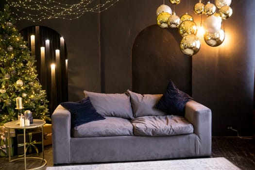 Christmas interior with a beautiful Christmas tree, sofa, light bulbs and dark background