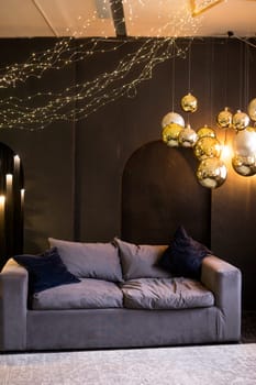 Christmas interior with a beautiful Christmas tree, sofa, light bulbs and dark background