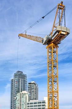 High-attitude crane and high-rise residential buildings on blue sky background.
