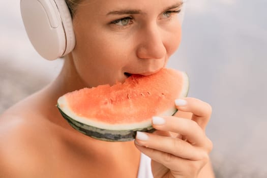 A woman is eating a watermelon slice. The watermelon is pink and green. The woman is smiling as she eats the fruit