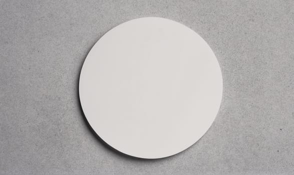 A white round plate sits on a gray concrete surface.