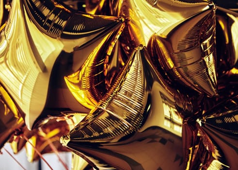 A cluster of shiny golden star-shaped balloons fills the space, reflecting warm light and creating a joyful atmosphere, perfect for any celebration or special event.
