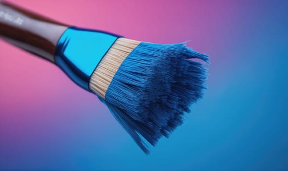 A close-up of a blue paintbrush with a wooden handle. The brush is resting against a gradient background that transitions from pink to blue.