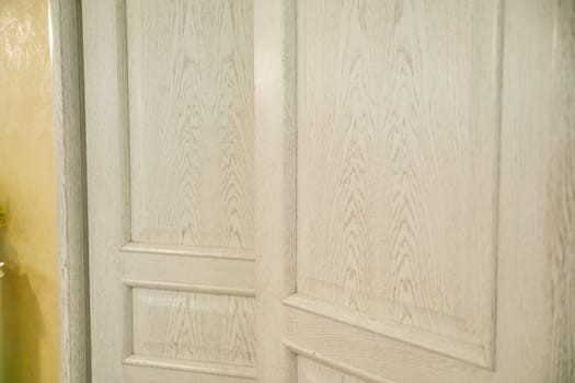 An empty room with walls covered by a large built-in wardrobe with vintage-style white wooden doors and yellow painted walls