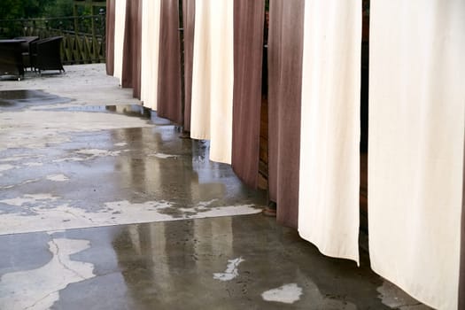 A long row of elegant white curtains gracefully hangs down on a sturdy concrete floor beneath them, creating a stylish atmosphere