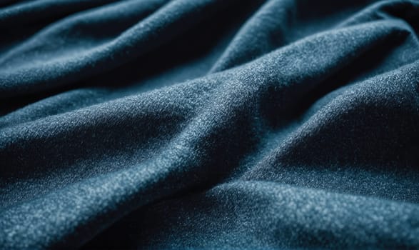 A soft blue fabric with a textured surface is folded in a way that highlights its natural drape. The folds and wrinkles show the fabric's texture and softness.