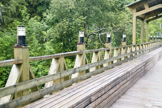 A beautiful wooden bridge stands prominently with lush trees in the background, creating a picturesque natural setting