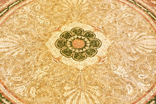 An intricately designed mosaic floor featuring a delicate flower beautifully positioned at the very center of the artwork
