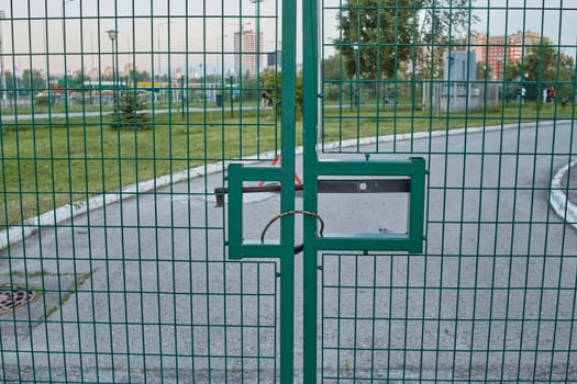 Green fence gate in front of the housing complex and road