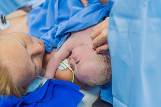 Baby on mother's chest immediately after birth in a hospital. The mother and newborn share a tender moment, emphasizing the bond and emotional connection. The medical staff ensures a safe and caring environment.