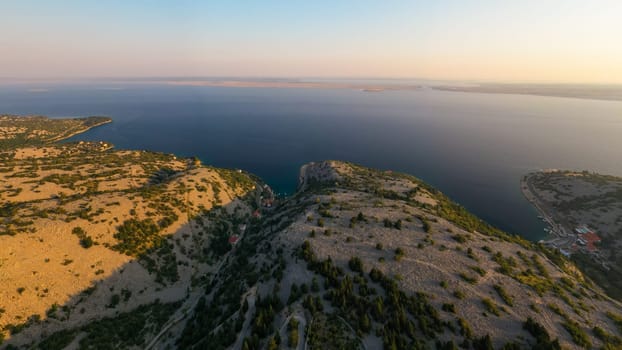 Aerial view of coastline and calm waters at sunset on a tranquil evening.