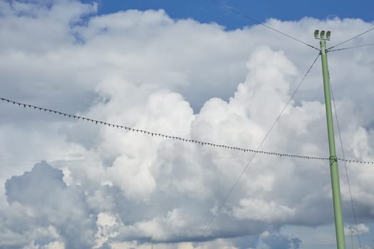 cloudy blue sky with light bulb garlands between the pillars