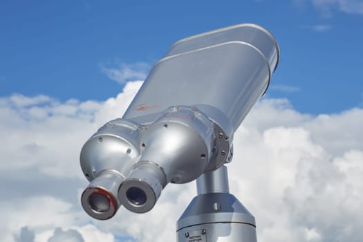 Street binoculars on a background of blue sky with clouds. Traveling , relaxing, walking around the city. Attractions.