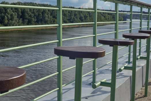 wooden empty stools on the riverbank, embankment. Rest , time for friends