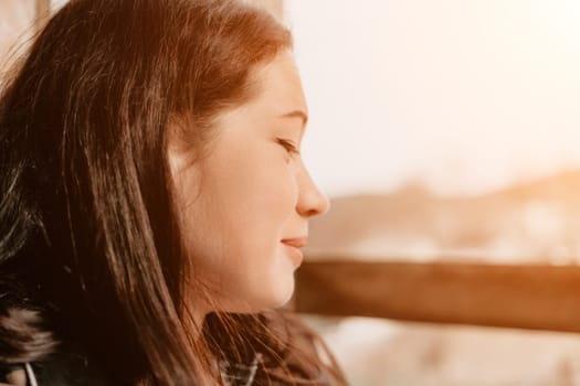A young woman with long brown hair, captured in profile, gazes off-camera with a soft expression.
