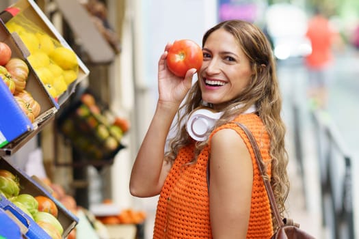 Latin happy and surprised woman holding organic delicious tomato shopping at organic food market