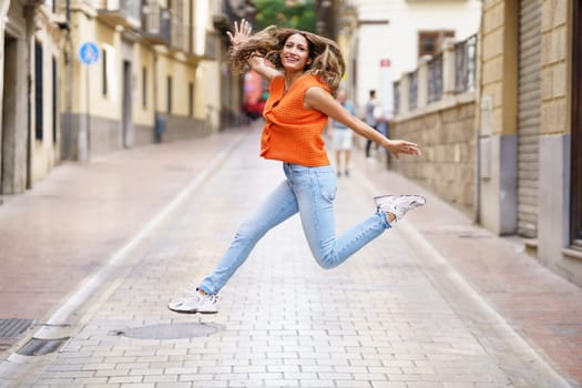 Full length portrait of a latin happy woman celebrating jumping free in the street