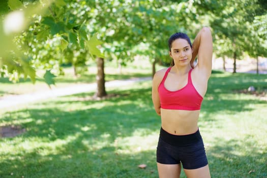 A dedicated athlete in bright activewear trains in a sunny park, surrounded by green trees, demonstrating commitment to fitness and wellbeing. It highlights motivation and a healthy lifestyle