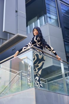 Vertical low angle view of a dancer posing leaning on a rail in the city