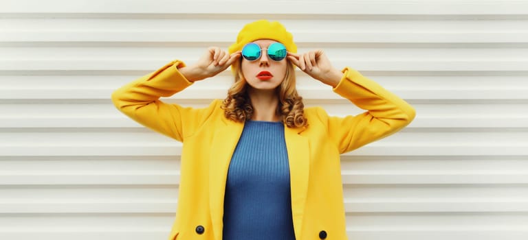 Autumn portrait of beautiful trendy young woman in yellow french beret hat, glasses, stylish girl posing on white background