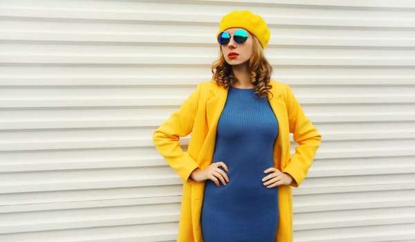 Autumn portrait of beautiful trendy young woman in yellow french beret hat, glasses, stylish girl looking away posing on white background