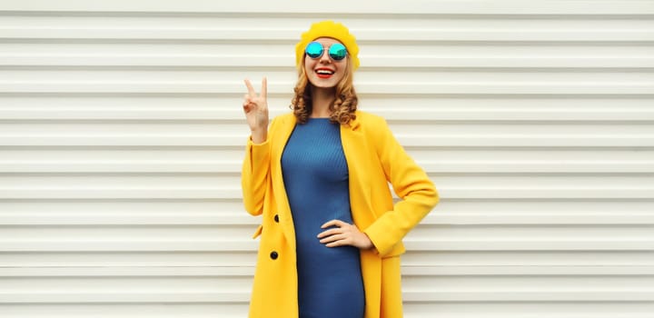 Autumn portrait of beautiful happy smiling woman in yellow french beret hat, stylish trendy girl posing on white background