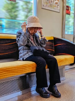 KYOTO, JAPAN - MAY 15, 2019: An older Japanese woman sitting on a train in Kyoto, Japan