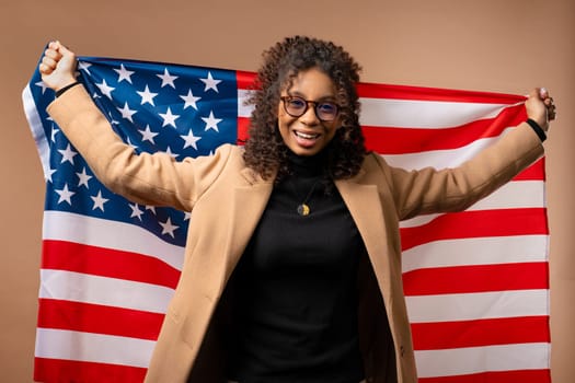 Smiling woman with national USA flag on beige background. American patriot, 4th of July - Independence day celebration, election, America, labor. US banner. High quality