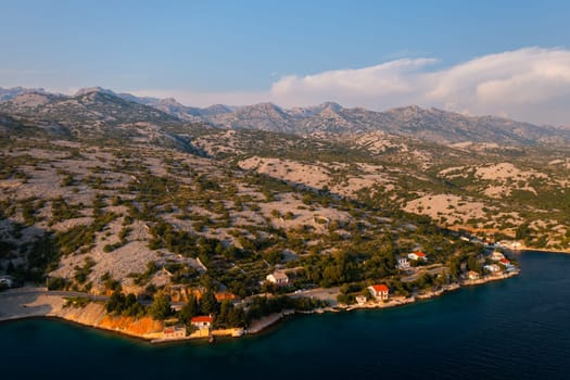 Serene coastal village in Croatia at sunset with hills in the background.