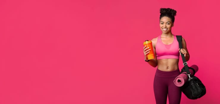 Portrait of happy fitness african girl with sporty bag, mat and shaker, enjoying healthy lifestyle
