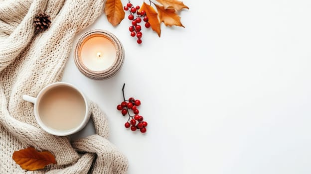 A warm beverage sits next to a knitted sweater, adorned with vibrant autumn leaves and red berries, creating a comforting seasonal atmosphere.