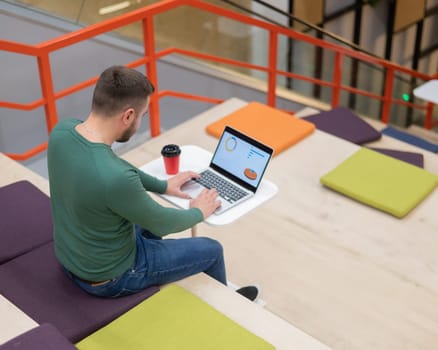 Caucasian man working on laptop in coworking space. Open space