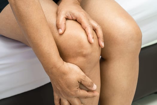 Asian lady woman patient touch and feel pain her knee, healthy medical concept.