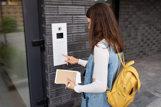 Door access control - a young woman student, holding a mail in her hands, enters the code to open the door. Door code