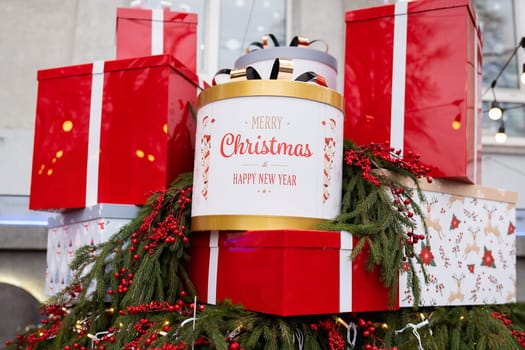 There are a lot of large bright and beautiful red boxes with gifts against the background of a Christmas tree and decorations. Christmas and New Years Eve 2022-2023