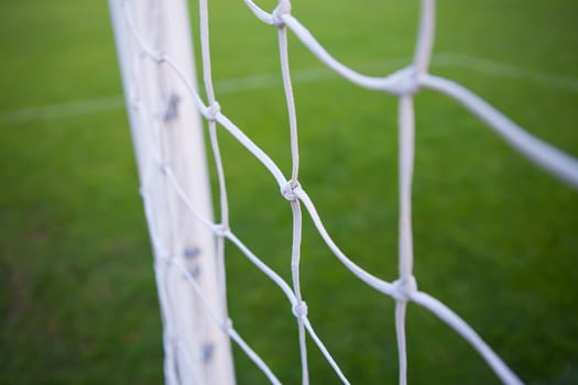 White mesh close-up on a soccer field, soccer goal. Green field