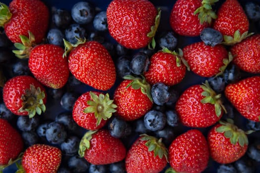 Background of assorted fresh berries of red juicy strawberries and blue blueberries close-up