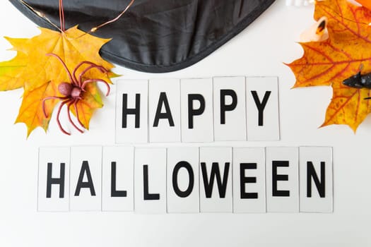 Happy Halloween lettering isolated on white background, holiday and party concept. Against the background of a spider, a mouse, a hat, yellow leaves
