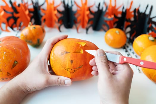 Halloween October 31st. A man cuts the face of a pumpkin with a knife. View from above
