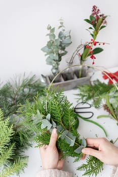 The process of making a Christmas wreath from needles, thuja, shimia, rosehip, pine twigs, chopped twigs for the wreath. The concept of preparation for Christmas and New Year